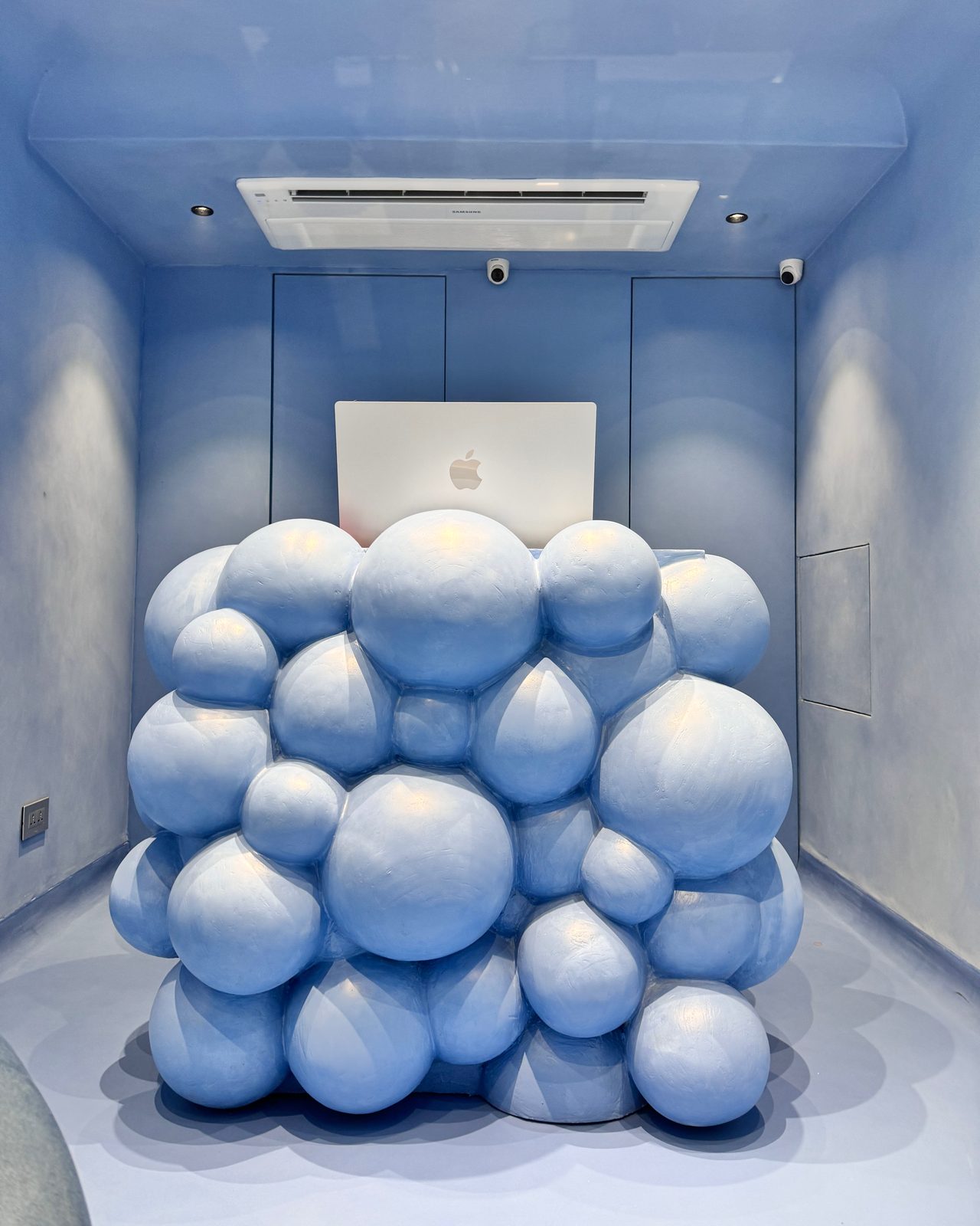 The store counter, a sculpture of blue spheres, with a laptop on top.