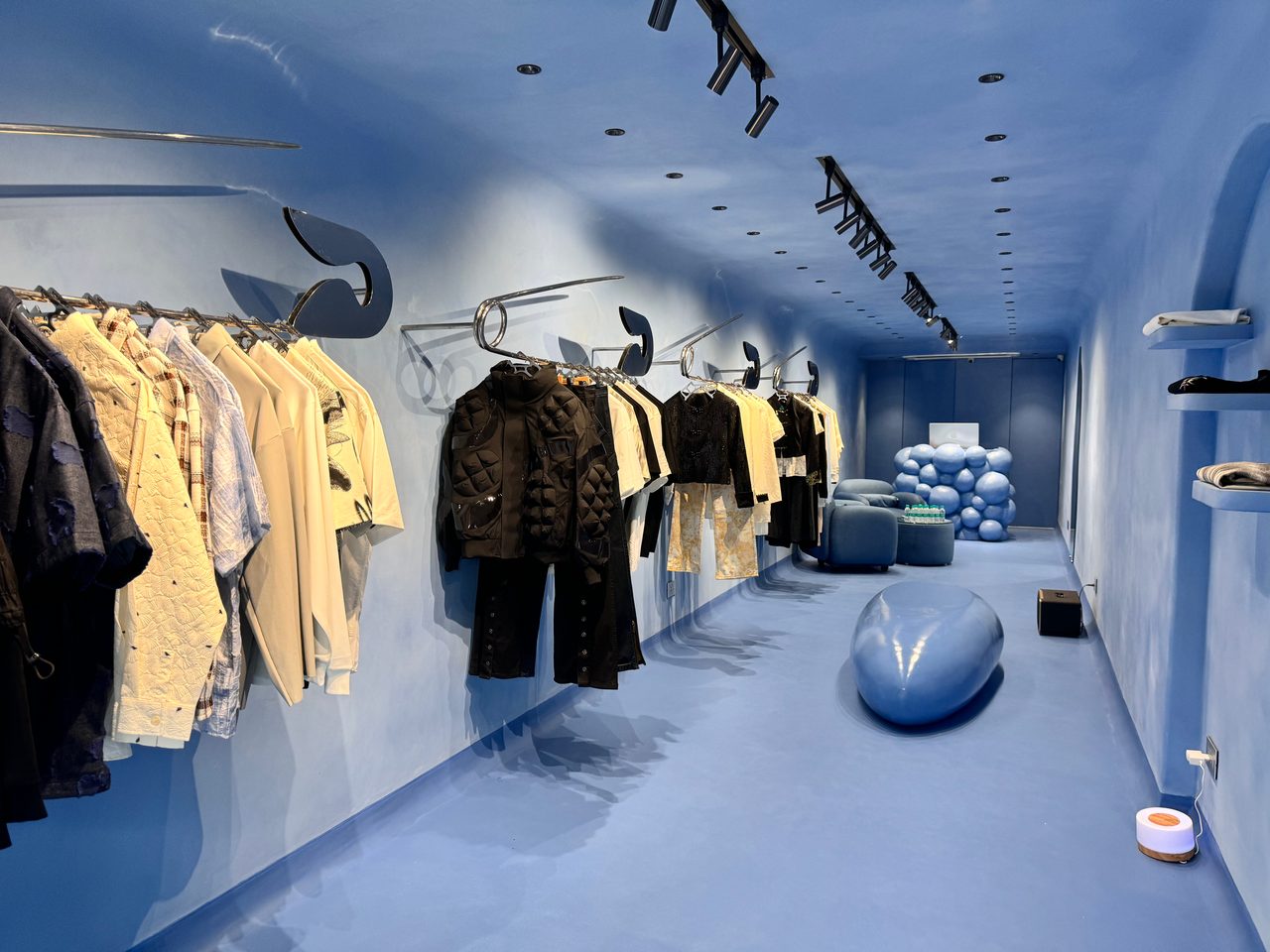 Inside the Hawk & Wolf store in Kala Ghoda: blue walls, floor and ceiling, clothes on safety-pin rails, and a blue counter made of spheres at the back.